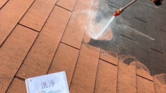 屋根塗装の工程において、高圧洗浄機を使って茶色の屋根瓦に付着した汚れを丁寧に洗い落としている実際の作業風景。